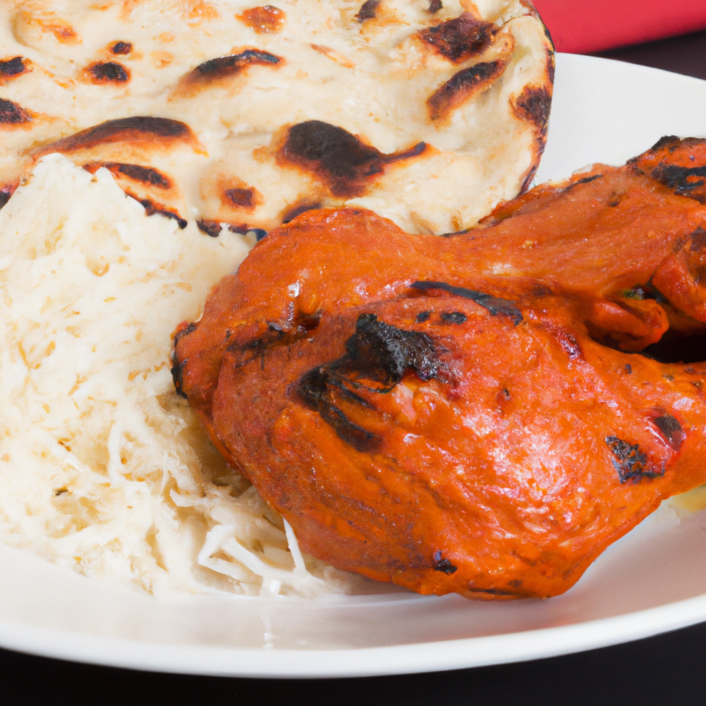 A plate of tandoori chicken with a side of rice and naan bread